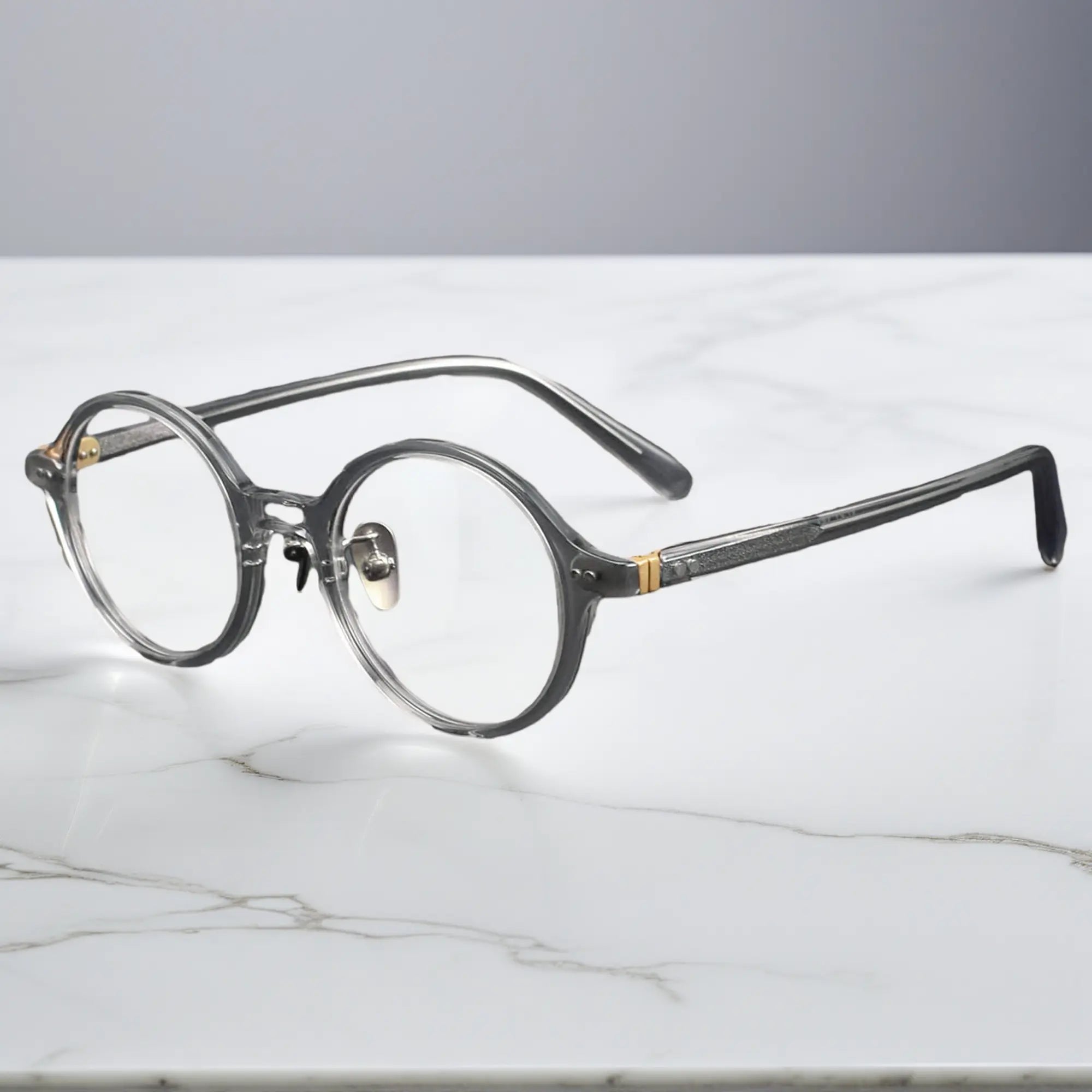 Clear grey round eyeglasses showing titanium nose pads and metal-insert hinges